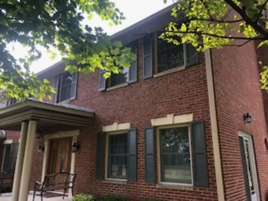 Windows with dark shutters on a two-story brick home in Lebanon, Indiana